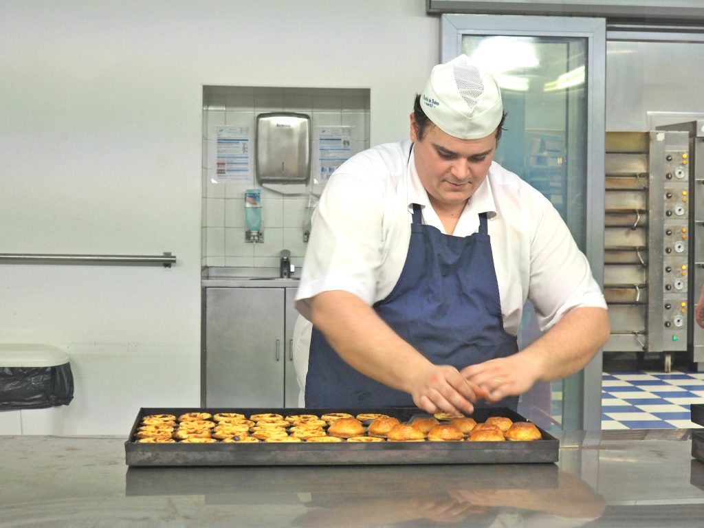 a cooc is preparing the traditional pastel de nata in Belem, Lisbon, Portugal